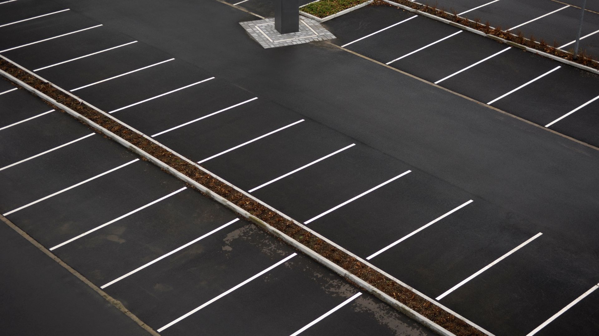 Aerial view of an empty outdoor parking lot with freshly painted white parking lines and no vehicles present.