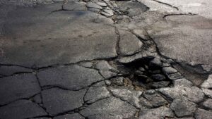 Cracked asphalt road surface with a large pothole