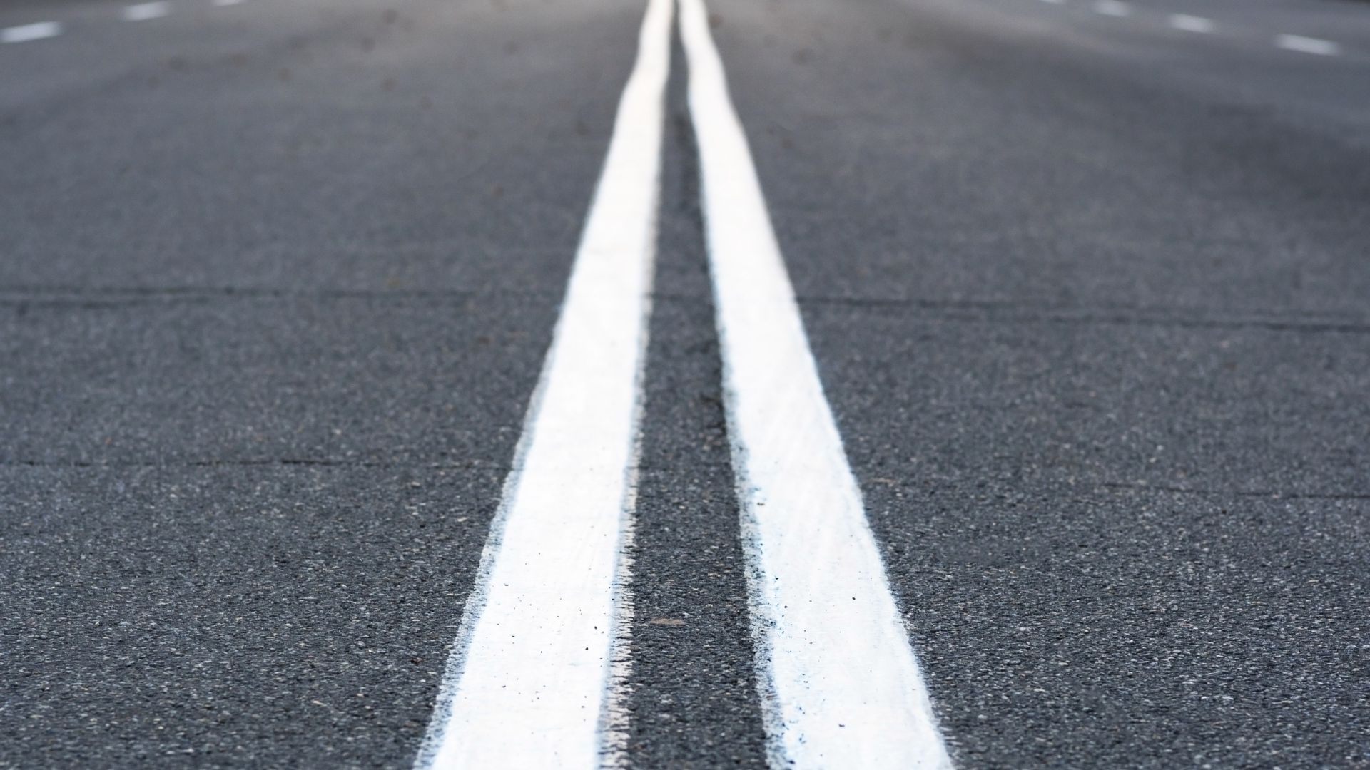 Close-up view of two solid white lines painted on an asphalt