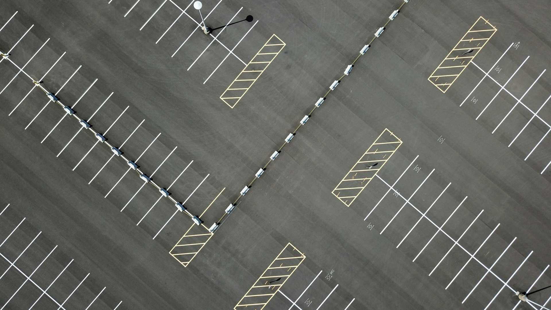 Top down view of paved parking lot with stripped parking spaces and no cars visible
