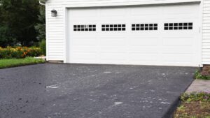 asphalt driveway leading to a white 2 car garage